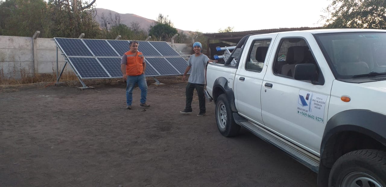 Camioneta del equipo cargando estructura de paneles solares, atardecer en zona rural