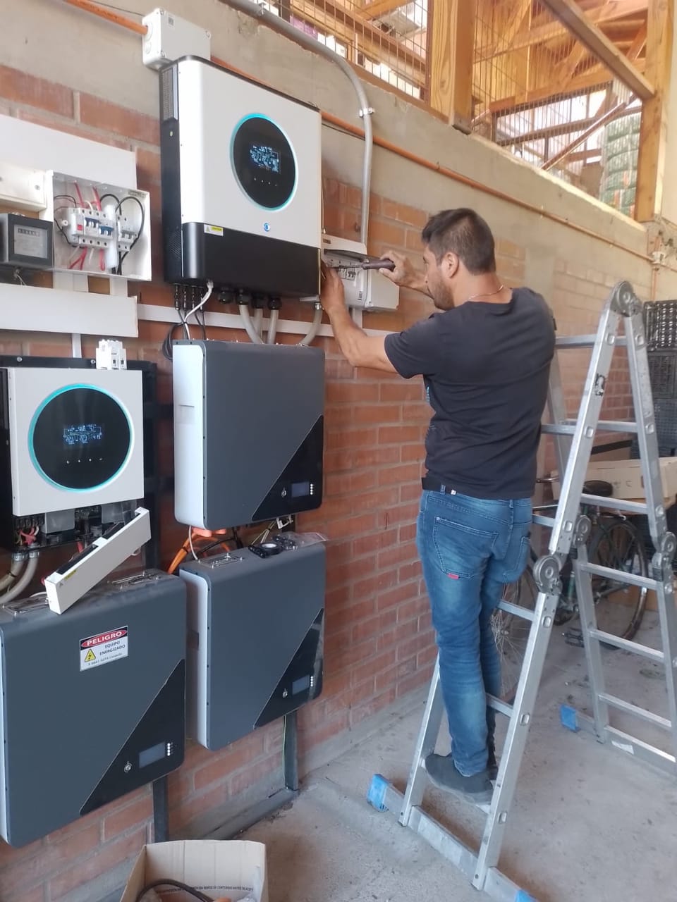 Técnico instalando inversor híbrido en muro de ladrillo