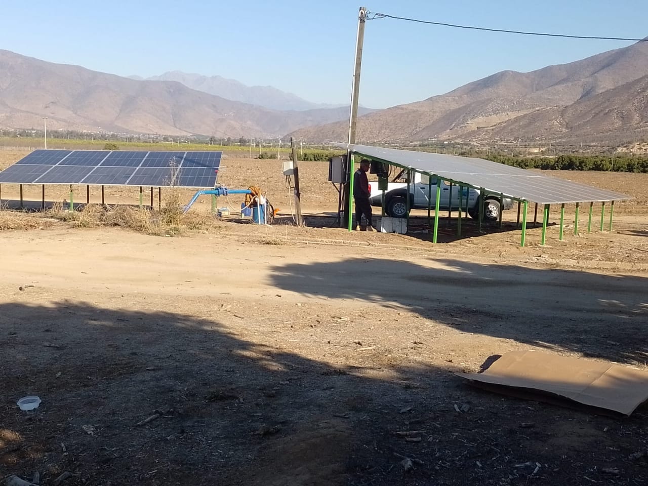 Estructura de paneles solares instalada en terreno agrícola, valle con cerros al fondo