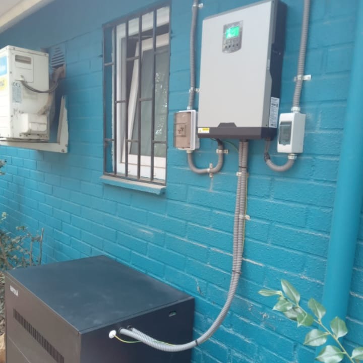 Inversor híbrido y banco de baterías instalados en muro exterior por Conexiones Solares